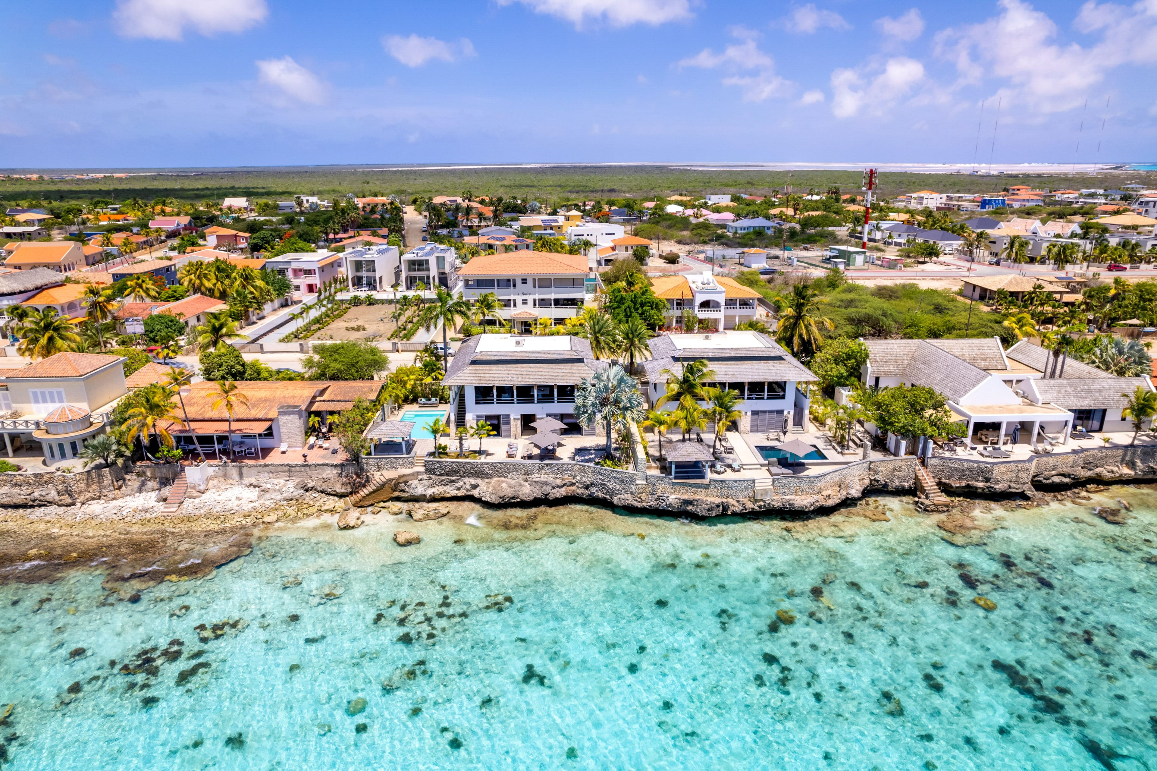 De westkust van Bonaire vanuit de lucht, met het rif, de rotskust en huizen aan het water
