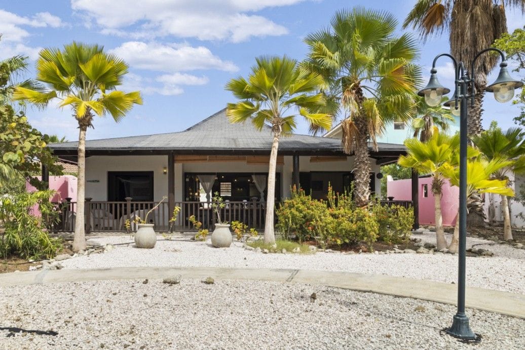 Villa derrière des palmiers et un jardin de gravier