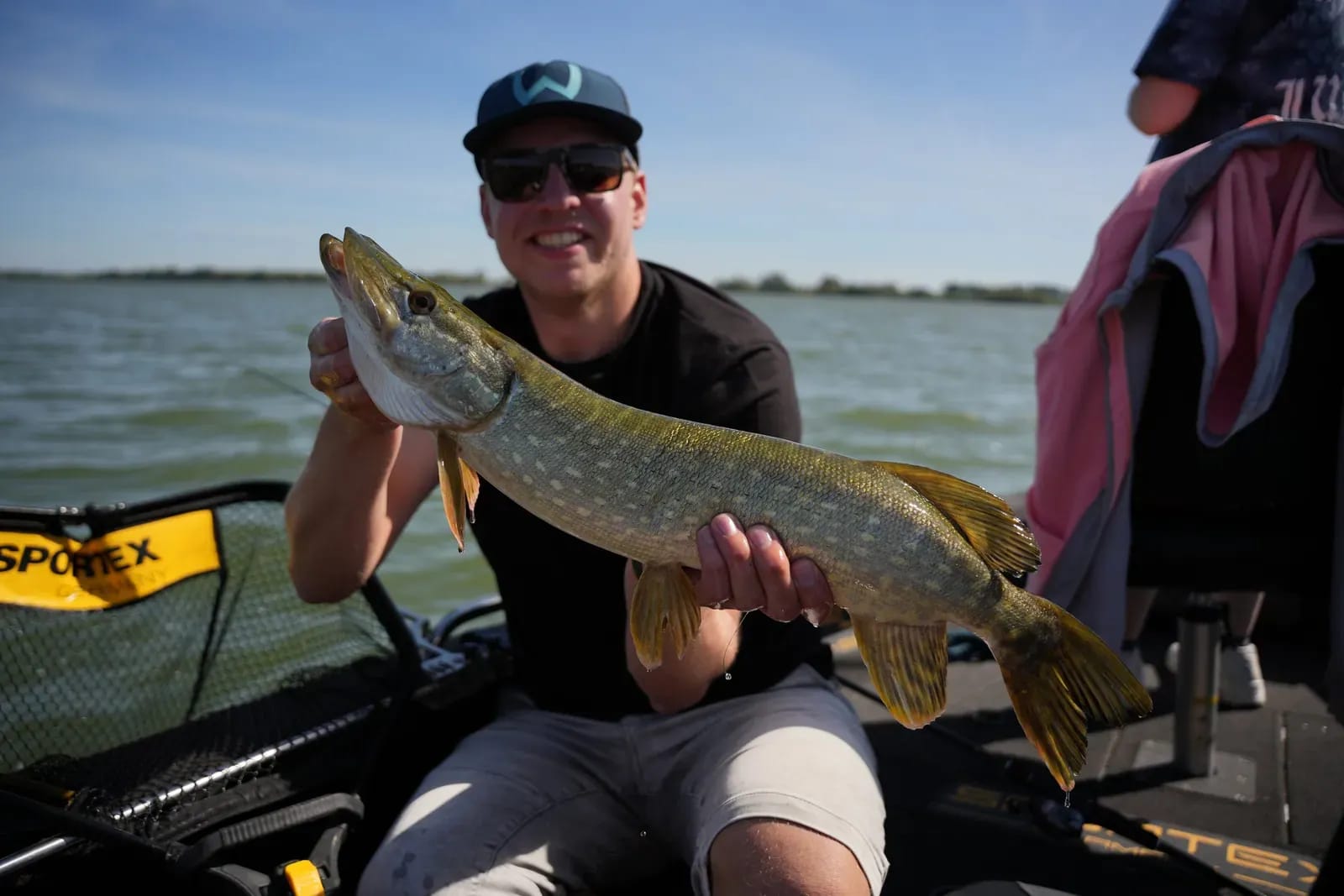 Lisa met de snoek die vlak voor de boot toesloeg, op een zonnige dag