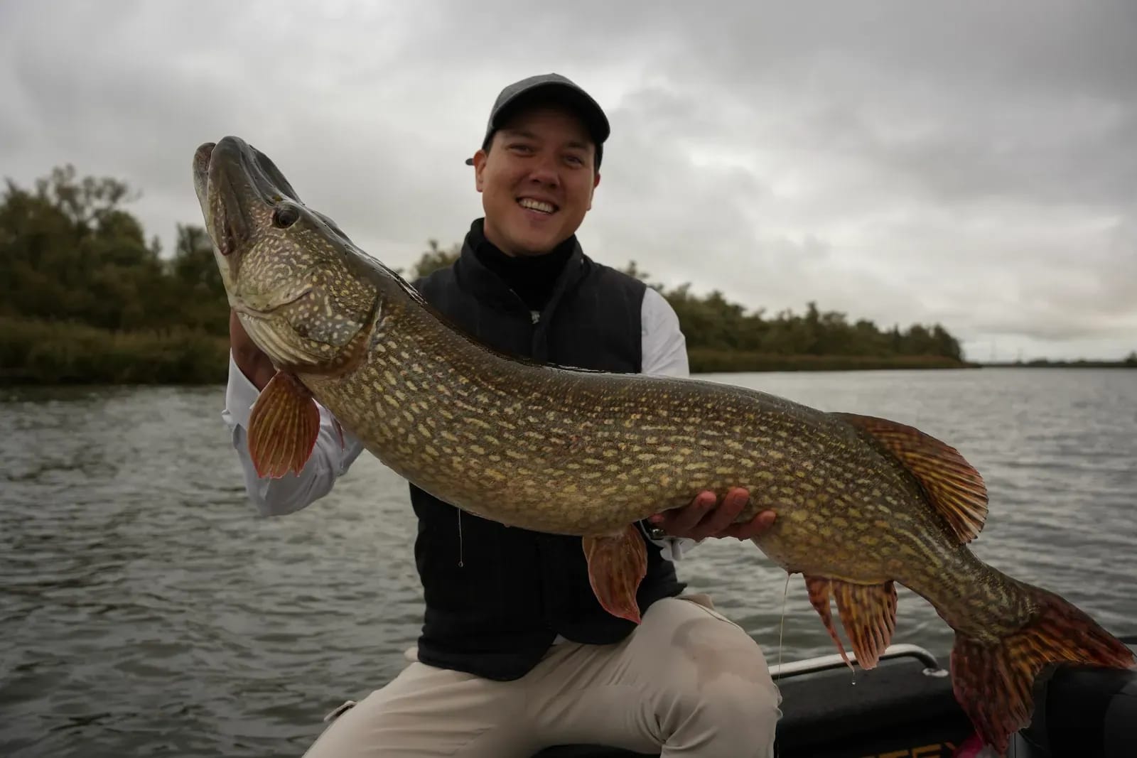 Danny met de snoek van 115 centimeter, met de Biesbosch-oever achter zich