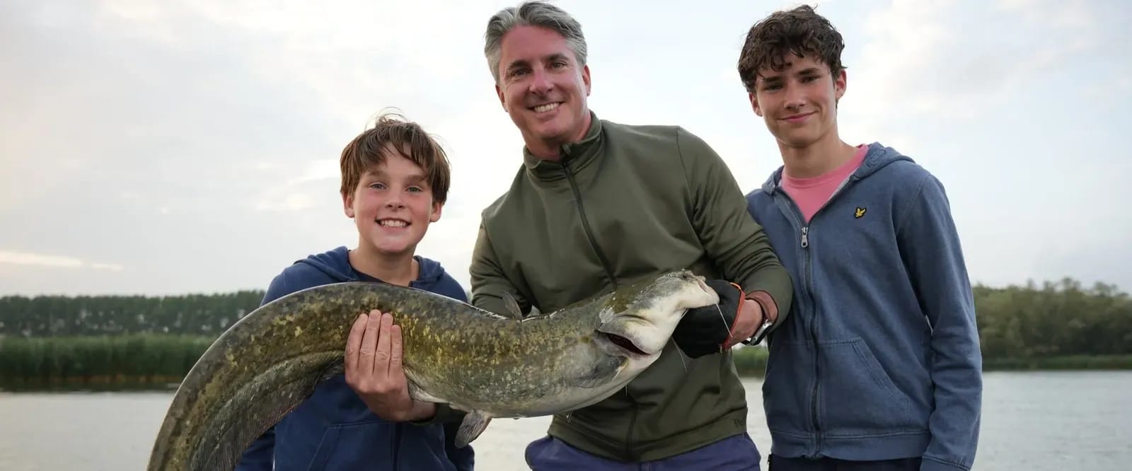 Een vader en zijn twee zoons houden samen de snoek van 115 centimeter vast
