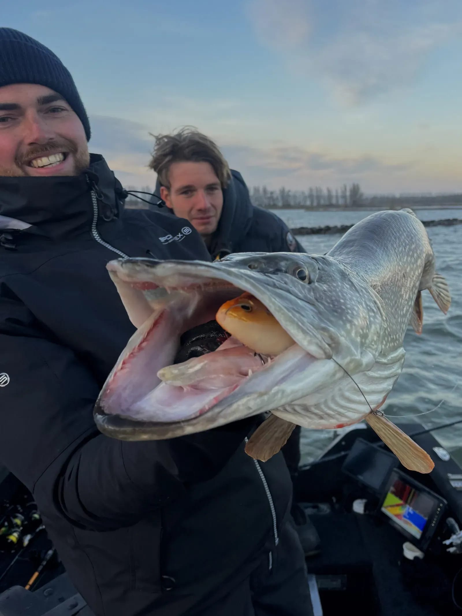 De opengesperde bek van de snoek, met het oranje kunstaas er nog in