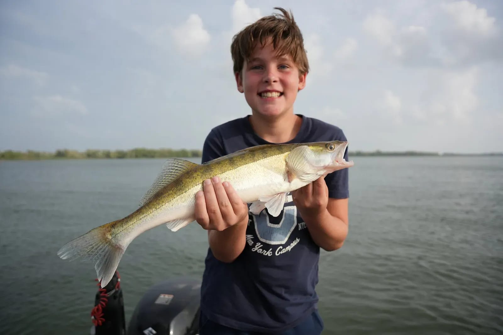 De jongste zoon met een snoekbaars die hij verticalend ving, op een zomeravond